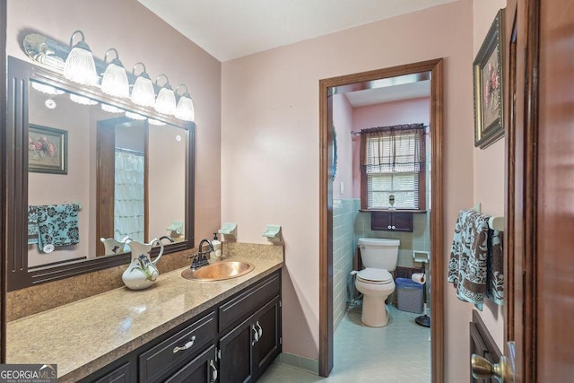 bathroom with toilet, tile patterned floors, tile walls, and vanity