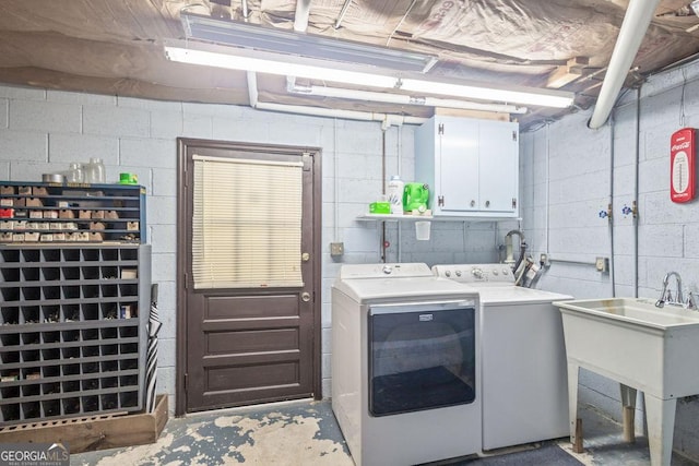 washroom featuring separate washer and dryer, cabinet space, and concrete block wall