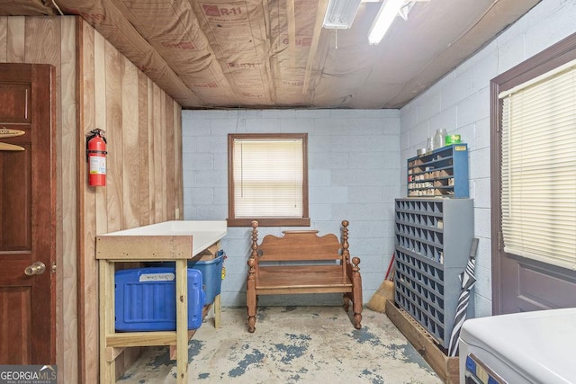 miscellaneous room with concrete block wall and unfinished concrete floors