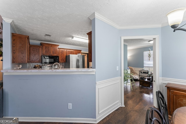 308 Dylan Way, Mcdonough, GA 30252 - kitchen with freestanding refrigerator, black microwave, wainscoting, a textured ceiling, and dark wood-style floors