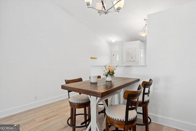dining area featuring baseboards, an inviting chandelier, and light wood-style floors
