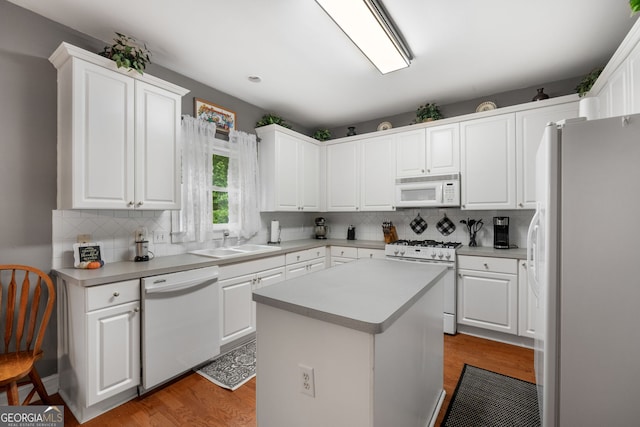 kitchen featuring decorative backsplash, a sink, white cabinets, white appliances, and light wood-style flooring