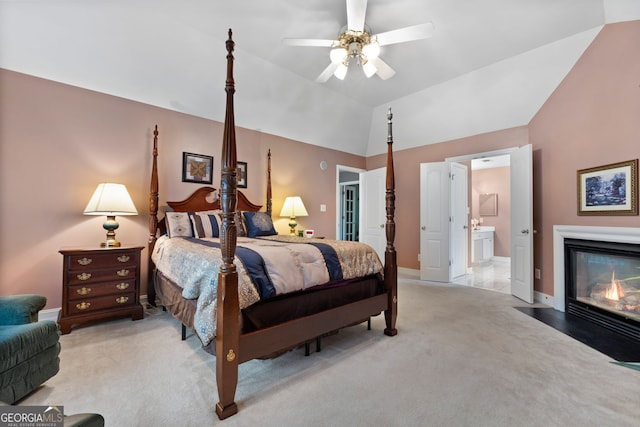 bedroom with baseboards, a fireplace with flush hearth, vaulted ceiling, and light carpet