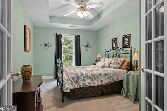 carpeted bedroom with visible vents, a raised ceiling, ceiling fan, and baseboards