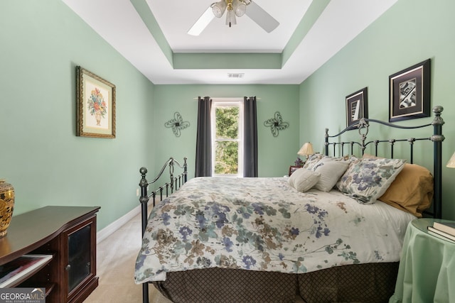 bedroom featuring visible vents, baseboards, ceiling fan, light colored carpet, and a raised ceiling