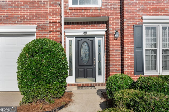 doorway to property featuring brick siding and an attached garage