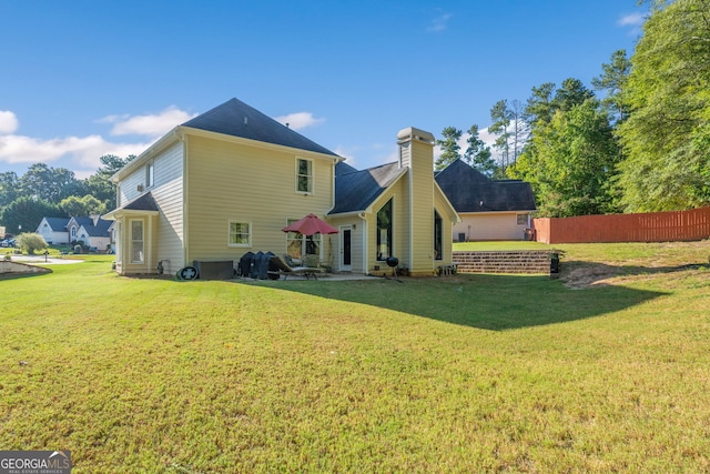 rear view of property with fence, a chimney, and a yard
