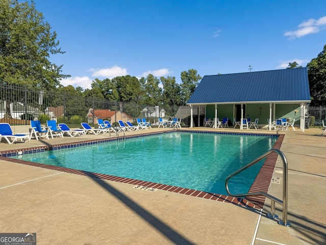 community pool with fence and a patio area