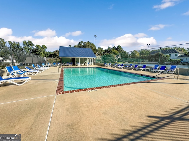 community pool with a patio and fence