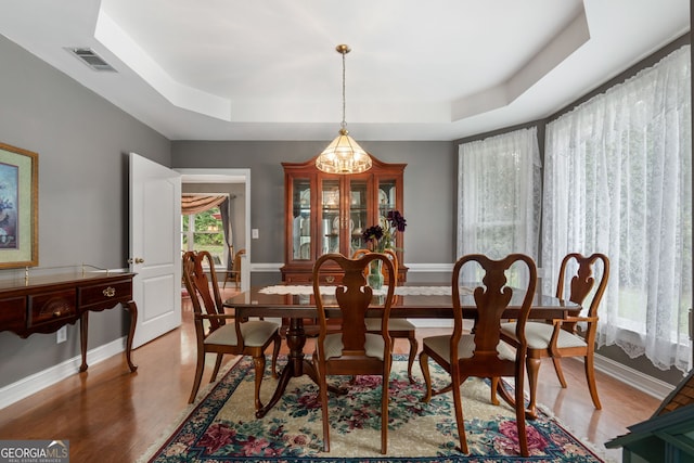 dining room with visible vents, a chandelier, light wood finished floors, and a raised ceiling