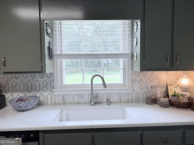 kitchen with a sink, dishwasher, light countertops, gray cabinets, and backsplash
