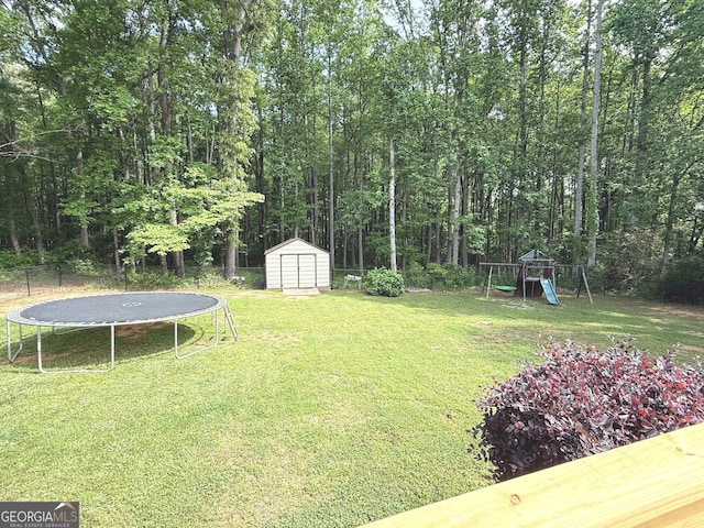 view of yard with a trampoline, fence, an outdoor structure, a playground, and a shed