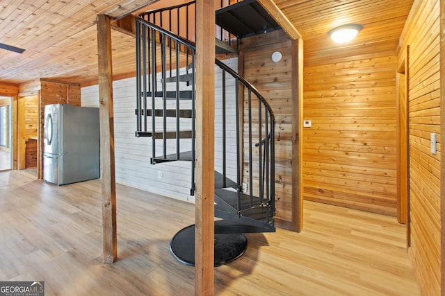 stairway with wooden ceiling, wood walls, and wood finished floors