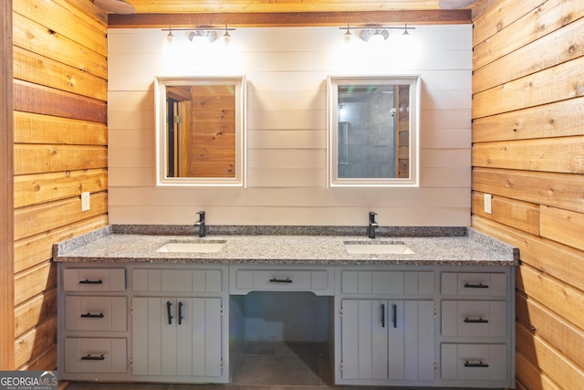 bathroom with double vanity, a sink, and wood walls