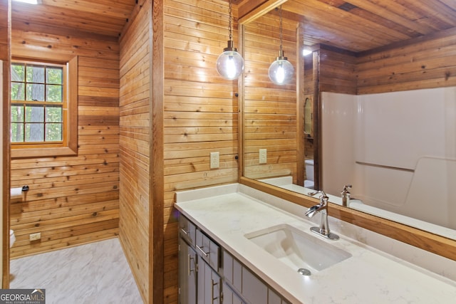 bathroom featuring vanity, toilet, wood walls, marble finish floor, and wooden ceiling