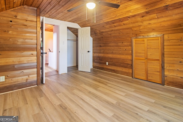 unfurnished bedroom featuring lofted ceiling, ceiling fan, wooden walls, wooden ceiling, and light wood finished floors