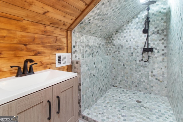 full bath with vanity, lofted ceiling, tiled shower, and visible vents