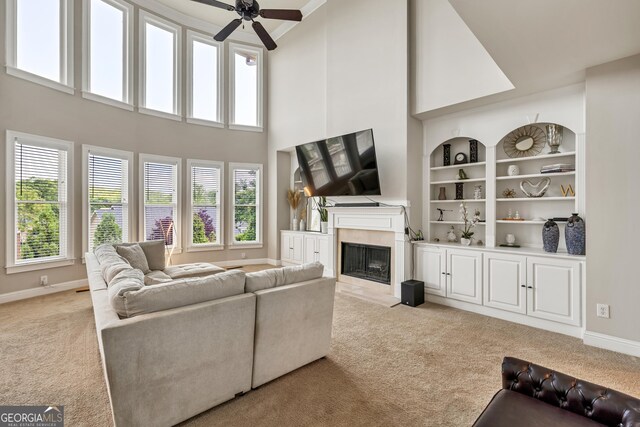 1584 Heartland Path, Hoschton, GA 30548 - living area featuring light carpet, a fireplace, ceiling fan, a towering ceiling, and built in shelves