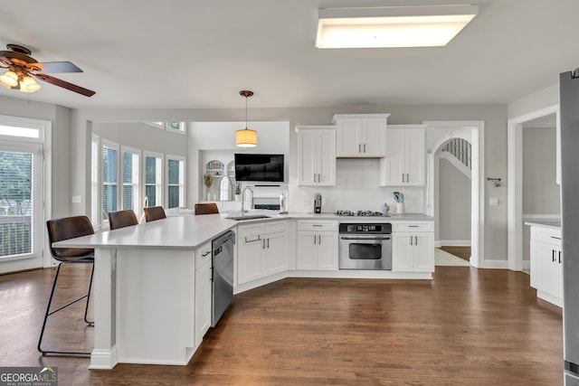 kitchen with stainless steel appliances, ceiling fan, a sink, light countertops, and a kitchen bar