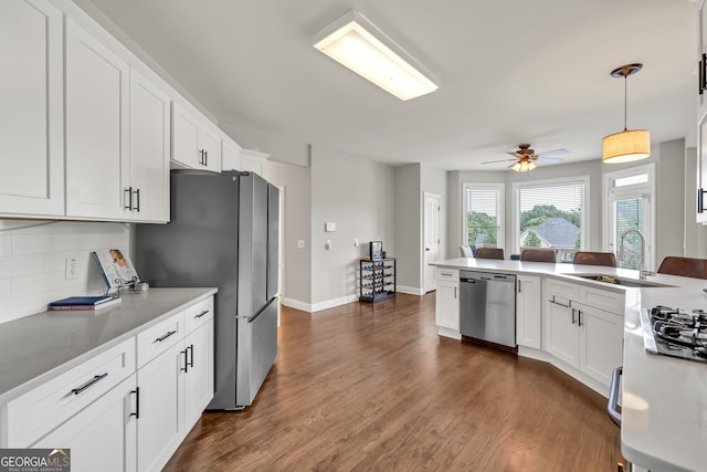 kitchen with stainless steel appliances, a sink, backsplash, and white cabinetry