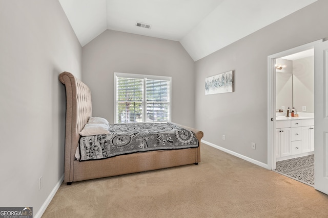 bedroom with light carpet, bar area, vaulted ceiling, baseboards, and ensuite bathroom