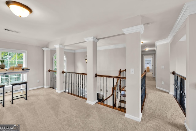 corridor with carpet flooring, an upstairs landing, baseboards, decorative columns, and crown molding