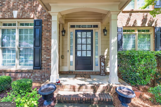 view of exterior entry featuring brick siding and a porch
