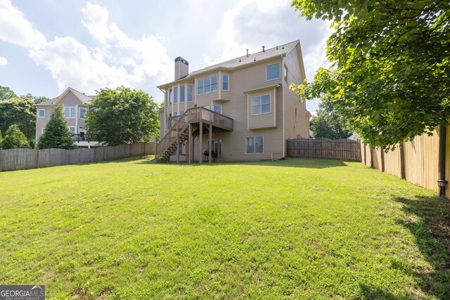 1584 Heartland Path, Hoschton, GA 30548 - back of property with stairs, a fenced backyard, a wooden deck, and a chimney