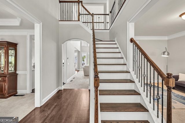 1584 Heartland Path, Hoschton, GA 30548 - staircase featuring arched walkways, wood finished floors, crown molding, carpet floors, and a high ceiling