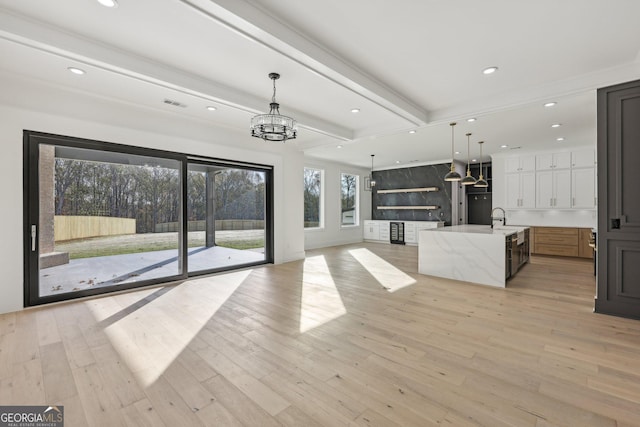 unfurnished living room with visible vents, light wood-type flooring, beamed ceiling, a chandelier, and recessed lighting