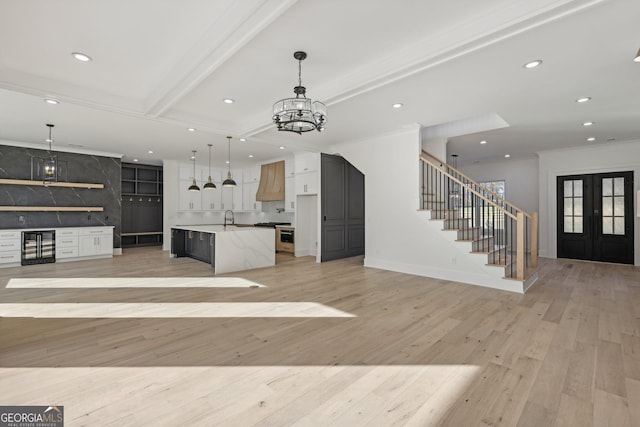 kitchen with hanging light fixtures, a sink, a notable chandelier, wine cooler, and open floor plan