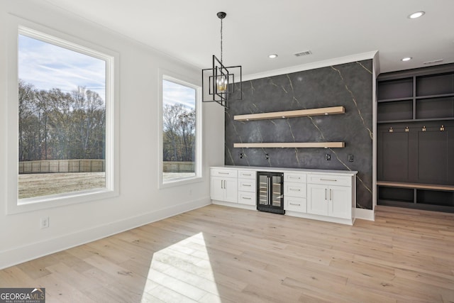 bar featuring a notable chandelier, light wood finished floors, beverage cooler, visible vents, and a bar