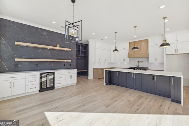 kitchen featuring light wood finished floors, light countertops, white cabinetry, recessed lighting, and wine cooler