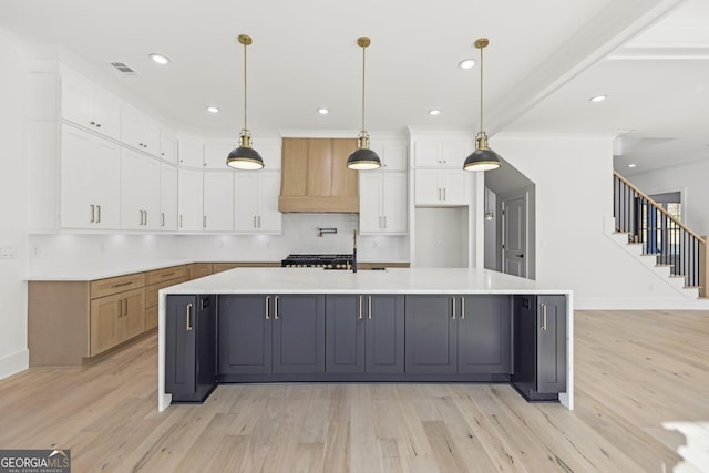 kitchen with visible vents, light wood-style flooring, backsplash, and white cabinetry