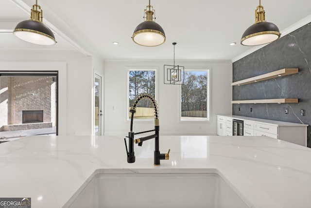 interior details with open shelves, pendant lighting, light stone countertops, recessed lighting, and a sink