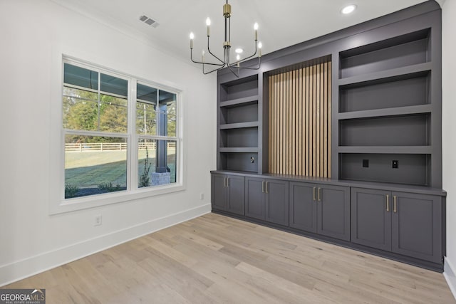 unfurnished dining area with visible vents, baseboards, light wood-style floors, built in shelves, and a notable chandelier