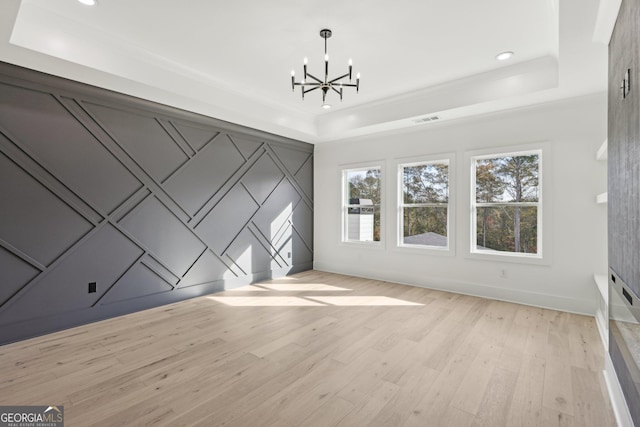 interior space featuring visible vents, a notable chandelier, a raised ceiling, and light wood-style floors