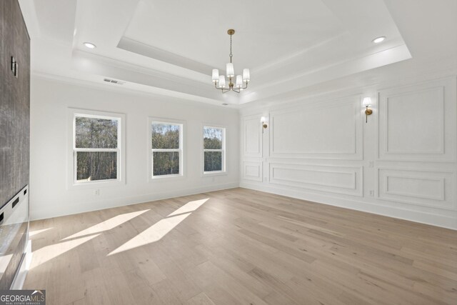 interior space with an inviting chandelier, a healthy amount of sunlight, a tray ceiling, and visible vents