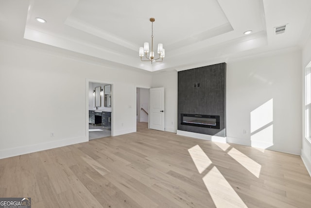 unfurnished living room featuring a chandelier, visible vents, and a raised ceiling