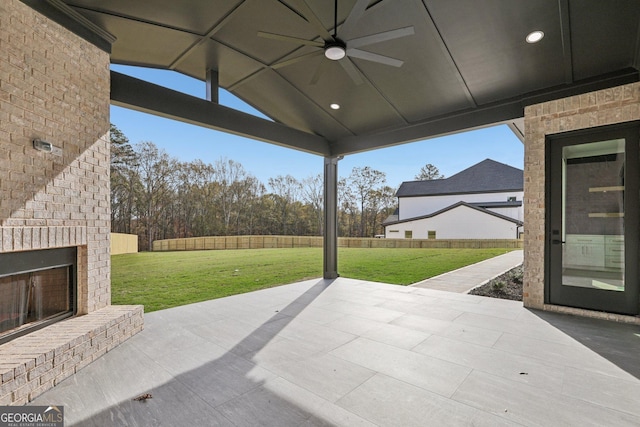 view of patio / terrace featuring a ceiling fan, fence, and an outdoor brick fireplace