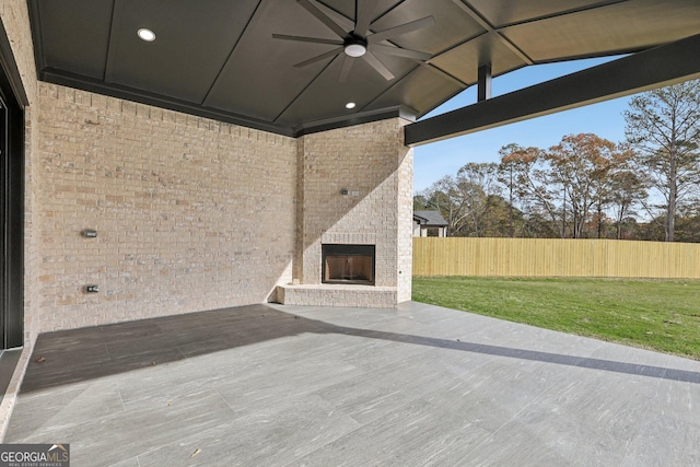 view of patio with fence, a ceiling fan, and an outdoor brick fireplace