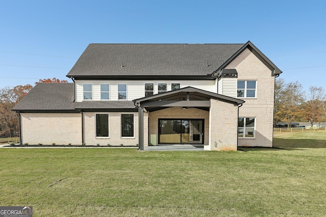 back of property featuring a lawn, a ceiling fan, a shingled roof, and brick siding