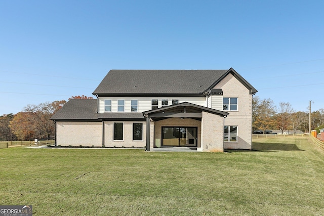 back of property with a yard, brick siding, and fence