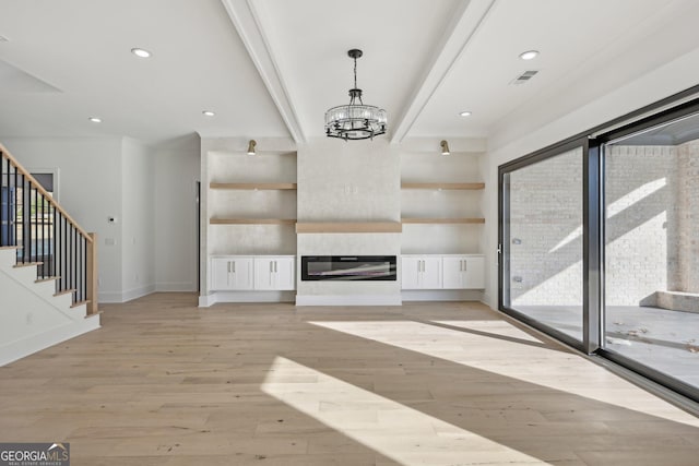 unfurnished living room featuring visible vents, stairs, baseboards, light wood-type flooring, and a notable chandelier