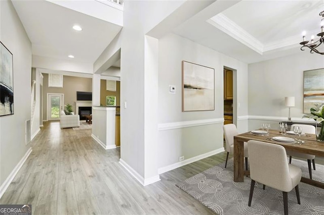 7712 Soaring Eagle Dr, Flowery Branch, GA 30542 - dining area featuring light wood-type flooring, a chandelier, a fireplace, recessed lighting, and crown molding