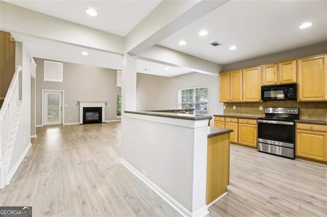 7712 Soaring Eagle Dr, Flowery Branch, GA 30542 - kitchen with stainless steel electric range, black microwave, dark countertops, light wood-type flooring, and decorative backsplash