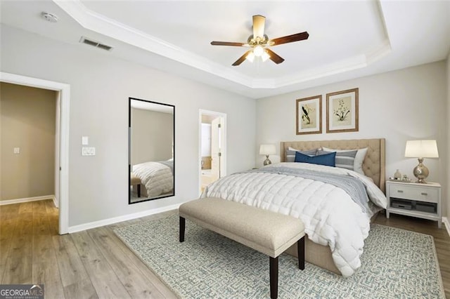 7712 Soaring Eagle Dr, Flowery Branch, GA 30542 - bedroom featuring a tray ceiling, wood finished floors, ceiling fan, and connected bathroom