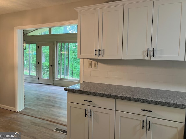 kitchen with white cabinetry, visible vents, light wood finished floors, and tasteful backsplash