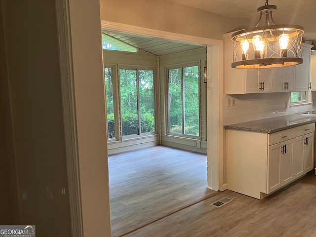 kitchen with visible vents, white cabinetry, wood finished floors, and an inviting chandelier