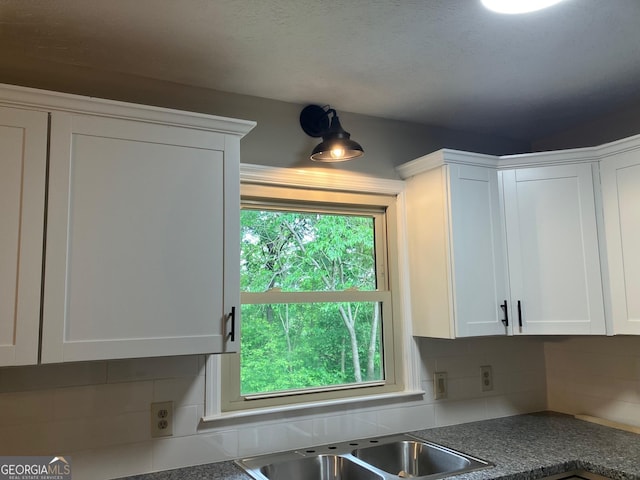 kitchen featuring a sink, white cabinets, dark countertops, and tasteful backsplash